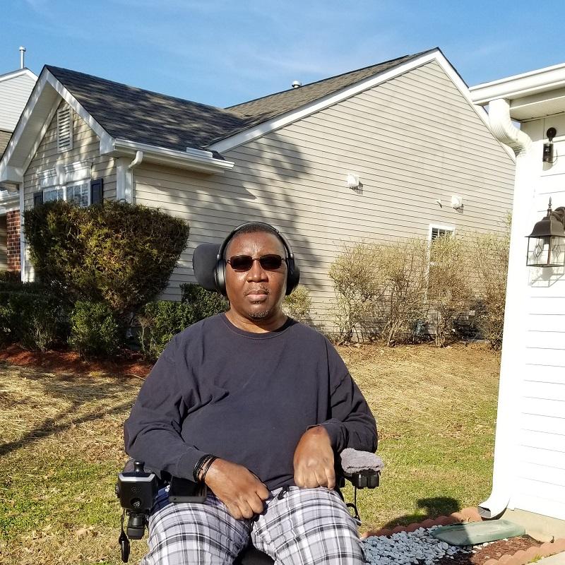 Stephany Golden is outside in his power chair wearing dark sunglasses.