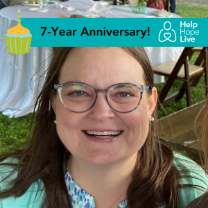 A teal banner with black text says 7-Year Anniversary! Next to it is the Help Hope Live logo in white and a colorful birthday cupcake graphic. Heart transplant recipient Linda Jara smiles while attending an outdoor wedding. She has shoulder-length light brown hair, green eyes, pearl earrings, and glasses with transluscent gray frames. She is wearing pastel blues and greens.