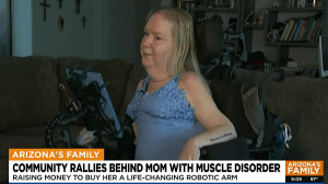 A screenshot of FOX news coverage of mom with spinal muscular atrophy Karole MacFarlane. Karole is seated in her black power chair. She has light skin and blonde hair. A caption reads ARIZONA'S FAMILY: Community Rallies Behind Mom with Muscle Disorder. Raising money to buy her a life-changing robotic arm.