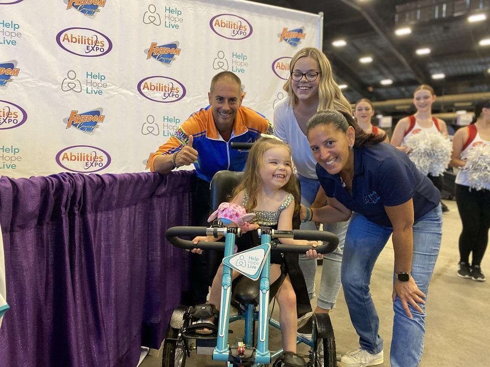 Kelly Green with 3-year-old Emberly on her new adaptive bike and family plus James Wall from Freedom Concepts, all at the Abilities Expo Phoenix.